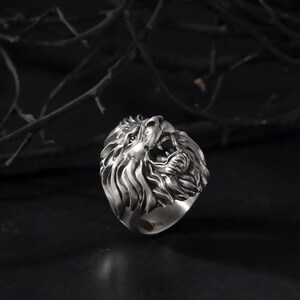 Puede incluir: Un anillo de plata con un dise&ntilde;o detallado de cabeza de le&oacute;n. La boca del le&oacute;n est&aacute; abierta y su melena est&aacute; esculpida de forma intrincada.