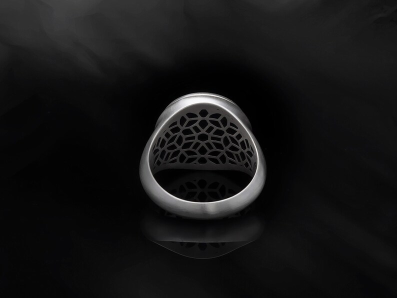 May include: A silver ring with a geometric design. The ring is made of metal and has a detailed pattern.
