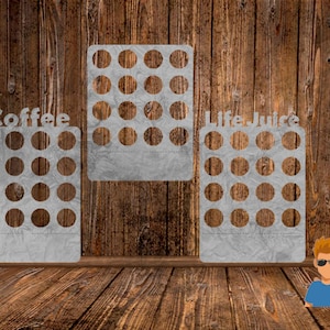 May include: Three silver metal organisers with circular cutouts for holding coffee pods. The organisers are labelled "Coffee", "Life", and "Juice".