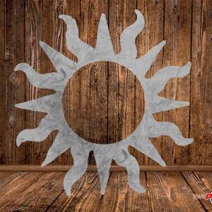 May include: A silver metal sun with a textured surface, against a wood background.