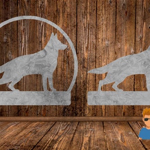 Puede incluir: Dos siluetas metálicas de perros pastor alemán sobre un fondo de madera. Un perro está en un círculo y el otro en una base rectangular.