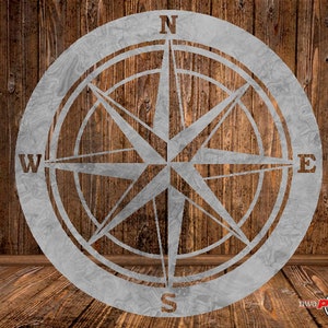 May include: A silver metal compass with a star design and the letters N, S, E, and W. The compass is on a wooden background.