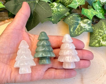 May include: Three carved crystal Christmas tree ornaments. One is green, one is white, and one is pink.