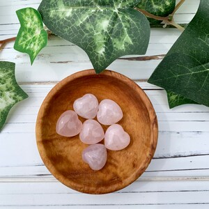 K&ouml;nnte beinhalten: Sechs herzf&ouml;rmige Steine aus rosa Rosenquarz in einer Holzschale.