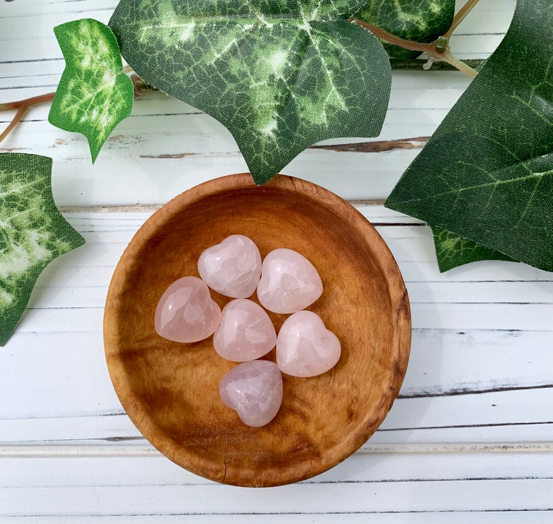 K&ouml;nnte beinhalten: Sechs herzf&ouml;rmige Steine aus rosa Rosenquarz in einer Holzschale.