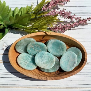 May include: A bowl filled with smooth, green, polished Amazonite stones. The stones are oval shaped and have a natural, earthy look.