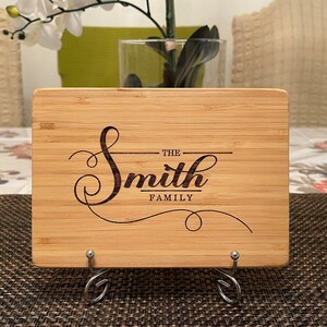 Op de afbeelding: Een gepersonaliseerd bamboe snijplank met de tekst "The Smith Family" gegraveerd in een decoratief handschrift.