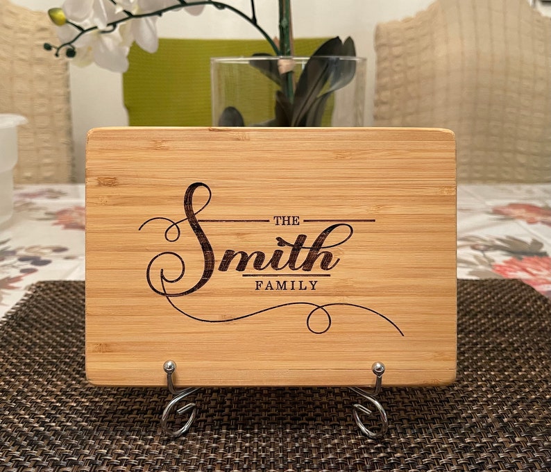 Op de afbeelding: Een gepersonaliseerd bamboe snijplank met de tekst "The Smith Family" gegraveerd in een decoratief handschrift.