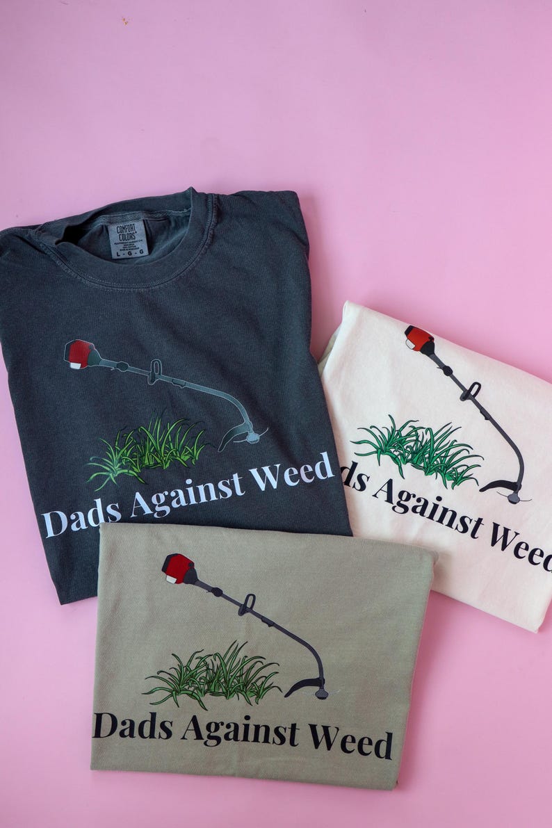 Pu&ograve; includere: Tre magliette con una grafica di un decespugliatore e il testo "Dads Against Weed". Le magliette sono di colore grigio antracite, beige e bianco.