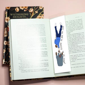 May include: Open book with a floral cover and a bookmark. The bookmark features an illustration of two figures, one upside down, with the text "DON'T YOU DARE GO BONKERS ON ME SHAWN!"