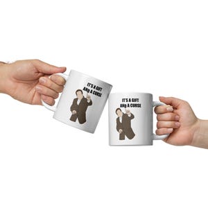 Może przedstawiać: Dwa białe ceramiczne kubki z czarnym tekstem i kreskówkową ilustracją osoby. Tekst na kubkach brzmi "It's a gift and a curse".