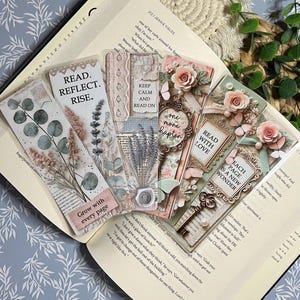 May include: A set of five rectangular bookmarks featuring floral and vintage-inspired designs. The bookmarks display text including READ. REFLECT. RISE., KEEP CALM AND READ ON, one more chapter, READ WITH LOVE, and EACH PAGE IS A NEW WONDER, with botanical motifs.