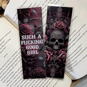 May include: Two rectangular bookmarks featuring dark, moody floral designs with deep red roses and thorny vines. One bookmark displays the white text "SUCH A FUCKING GOOD GIRL" in a bold font, while the other features a detailed, ornate skull illustration.