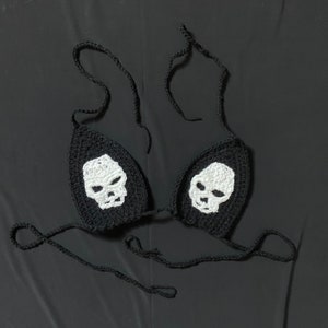 May include: Black crochet bikini top with white skull designs.