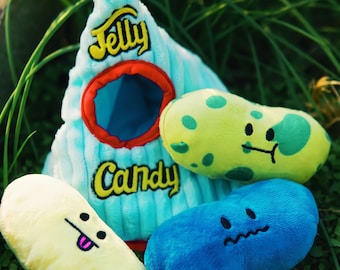 May include: A blue plush toy shaped like a rocket with the words "Jelly Candy" on the side. There are three bean-shaped plush toys with faces on them: one yellow, one green, and one blue.
