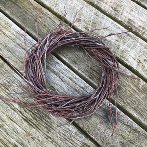 May include: A brown twig wreath on a wooden surface.