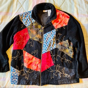 May include: A black fleece jacket with a zipper closure and a patchwork design. The patches are made of different fabrics and colors, including red, blue, and gold. The jacket has a quilted lining and is embroidered with floral designs.