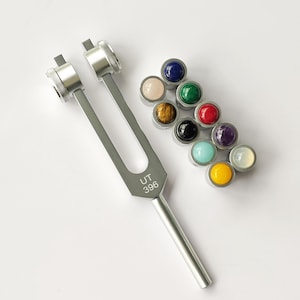 May include: A silver tuning fork with the inscription "UT 396" and a set of 10 small round gemstone crystals in various colors, including blue, green, red, yellow, and white.