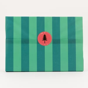 Könnte beinhalten: Ein Geschenk, verpackt in Papier mit vertikalen Streifen in Grün- und Türkistönen. Ein roter runder Aufkleber mit einem schwarzen Baum befindet sich in der Mitte der Verpackung. Das Geschenkpapier hat ein festliches Design.