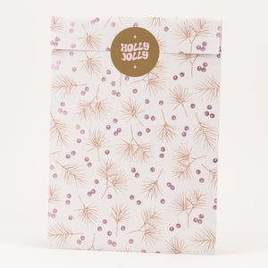 Könnte beinhalten: Eine weiße Geschenktüte mit einem sich wiederholenden Muster aus goldfarbenen Tannennadeln und kleinen lila Beeren. Auf der Vorderseite befindet sich ein goldener Aufkleber mit den Worten "HOLLY JOLLY" in rosa Schrift.