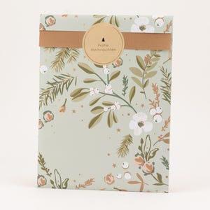 Könnte beinhalten: Ein verpacktes Geschenk mit einem hellgrünen Blumendesign mit weißen Blüten, grünen Blättern und braunen Akzenten. Ein braunes Band und ein runder Aufkleber mit deutschem Text umwickeln das Geschenk.