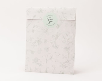 Pode incluir: Uma sacola de presente rosa claro com um padrão floral em verde claro. A sacola tem um adesivo circular que diz "For you" com as palavras "You are the best" e "Lots of love and kisses".