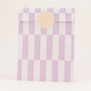 Könnte beinhalten: Geschenktüte aus Papier mit einem lila-weißen Karo- und Streifenmuster. Ein runder, hellpfirsichfarbener Aufkleber mit Herzdesign befindet sich auf der Klappe. Für kleine Geschenke oder Leckereien.