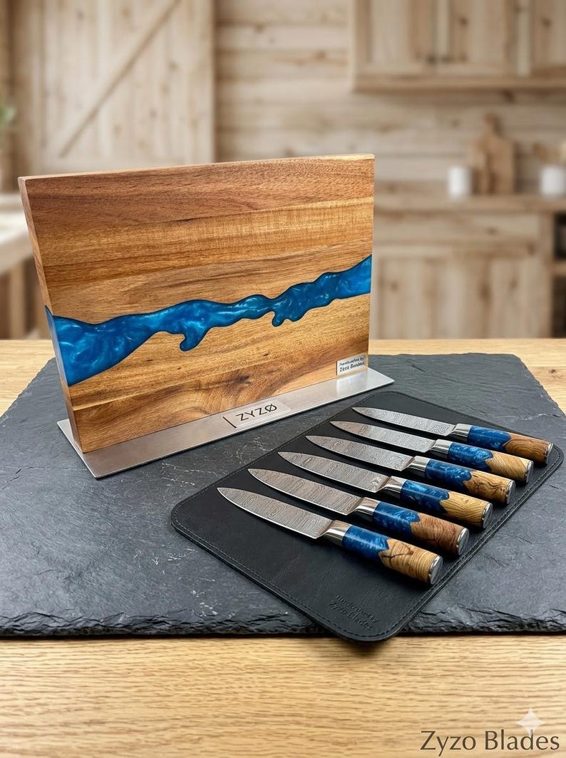 K&ouml;nnte beinhalten: Ein Messerblock aus Holz mit einem blauen Harzfluss-Design, kombiniert mit einem Satz von sechs Messern. Die Messer haben gemusterte Klingen, blaue Harzgriffe und Holzakzente. Der Messerblock und die Messer werden auf einer schwarzen Oberfl&auml;che pr&auml;sentiert.