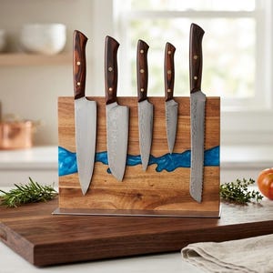 K&ouml;nnte beinhalten: Ein Set aus f&uuml;nf K&uuml;chenmessern mit Holzgriffen und silbernen Klingen, pr&auml;sentiert auf einem Messerblock aus Holz mit einem blauen Harzfluss-Design. Die Messer sind unterschiedlich gro&szlig;, darunter ein Brotmesser.