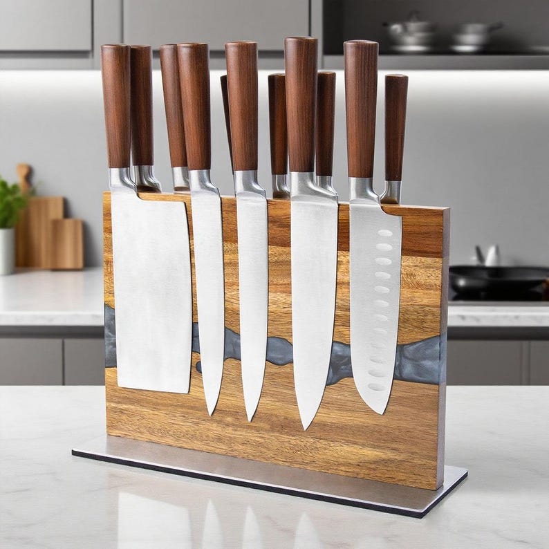 K&ouml;nnte beinhalten: Ein Set K&uuml;chenmesser mit Holzgriffen, das auf einem magnetischen Messerblock aus Holz ausgestellt ist. Die Messer haben silberne Klingen. Der Messerblock hat eine nat&uuml;rliche Holzmaserung und einen grauen Harzakzent.