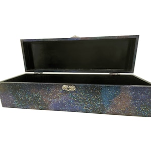 May include: A black wooden box with a glittery, iridescent finish. The box is open, revealing a black interior. The box has a silver latch.