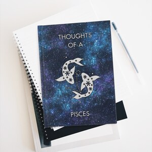 May include: A blue and purple galaxy-themed journal with a silver Pisces zodiac symbol and the text "Thoughts of a Pisces".