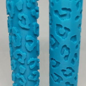 May include: Two blue textured paint rollers with a cheetah print design. The roller on the left is a positive print, and the roller on the right is a negative print.  Cheetah Print Texture Roller.