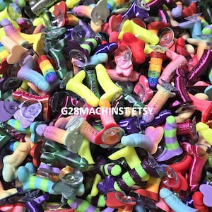 May include: A large collection of small, phallic-shaped plastic figurines in various colors including neon yellow, purple, pink, green, and rainbow gradients. Each figurine features a small clear suction cup at the base and the text NICE PARKING.