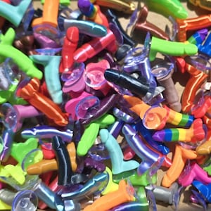 Peut inclure: Une grande collection de petites figurines en plastique en forme de phallus dans une variété de couleurs vives, notamment vert néon, orange, bleu, rose, noir et rayures arc-en-ciel. Chaque figurine possède une ventouse circulaire transparente.