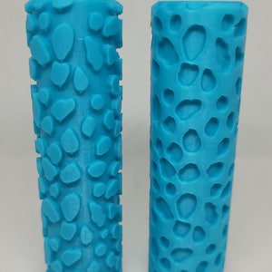 Pode incluir: Dois rolos de textura de plástico azul para pintar. O rolo à esquerda é um padrão positivo, e o rolo à direita é um padrão negativo. Ambos os rolos têm um design de pele de leopardo.
