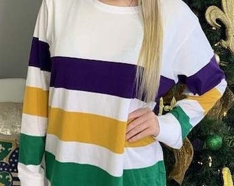May include: White long-sleeved shirt with horizontal stripes in purple, gold, and green.