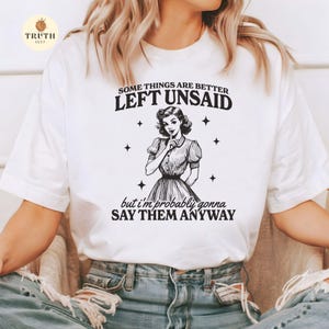 May include: White t-shirt with a black and white illustration of a woman with her finger to her lips. The text on the shirt reads "Some things are better left unsaid but I'm probably gonna say them anyway."