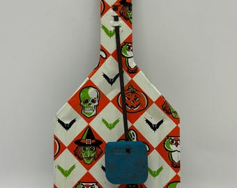 May include: Vintage Halloween noisemaker with a white, orange, and black diamond pattern. The design features green skulls, bats, witches, owls, and pumpkins. A blue plastic piece is attached to the noisemaker with a black wire.