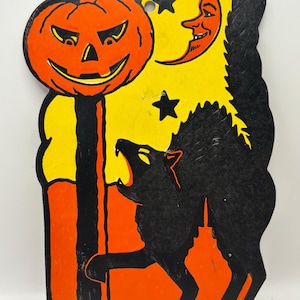 May include: Vintage Halloween decoration featuring a carved orange pumpkin, a black cat, a smiling crescent moon, and stars against a yellow background. The decoration is made in the U.S.A. and has a retro design.