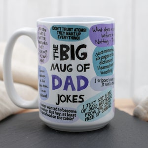 May include: A white ceramic mug with a large handle, featuring the text "The Big Mug of Dad Jokes" in black and purple. The mug is covered in various jokes in speech bubbles. The mug is on a black surface.