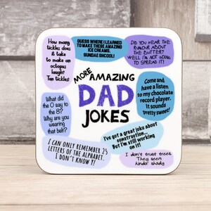 May include: A square coaster with the words "More Amazing Dad Jokes" in a playful font. The coaster features various jokes in speech bubbles, with a light background and colorful text.