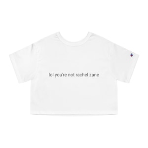 May include: White cropped t-shirt with short sleeves and a Champion logo on the right sleeve. The text "lol you're not rachel zane" is printed on the front of the shirt.