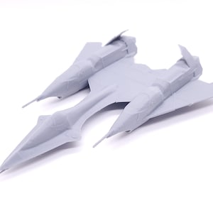 May include: A gray plastic model of a futuristic spaceship with two wings and a pointed nose.