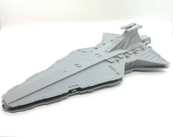 May include: A gray, detailed model of a spaceship with a long, narrow body and a pointed nose. The model has a series of small, rectangular windows along the side and a large, flat surface on top.