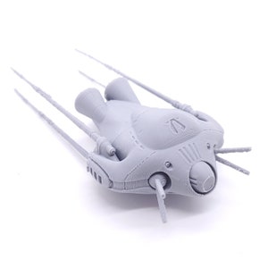 Puede incluir: Modelo de nave espacial gris claro con múltiples antenas sobresalientes. El modelo presenta componentes de motor detallados y un cuerpo central con un emblema estilizado. El diseño sugiere un tema de ciencia ficción o fantasía.