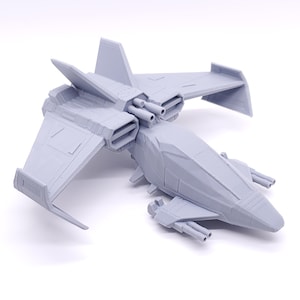 May include: A grey 3D printed model of a futuristic spaceship with two wings and a pointed nose. The spaceship has multiple cannons and engines.