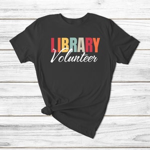May include: Black t-shirt with the text "LIBRARY Volunteer" in rainbow colors.