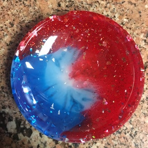 May include: A round, red, white, and blue resin trinket dish with glitter embedded in the resin.