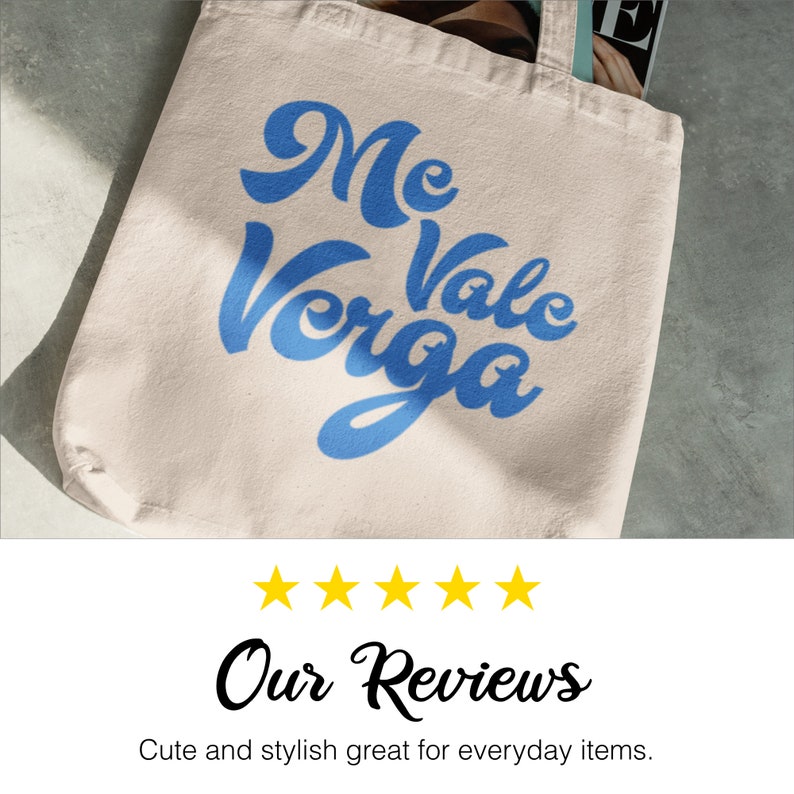 以下が含まれることがあります： クリーム色のトートバッグ。青い筆記体で「Me Vale Verga」と書かれています。丈夫な生地で作られており、シンプルなデザインです。バッグの中には雑誌が見えます。